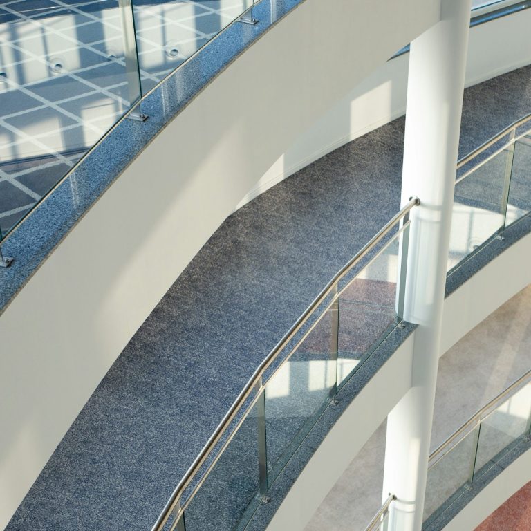 Überblick über geschwungene, moderne Treppen mit Glasgeländern und heller Beleuchtung.